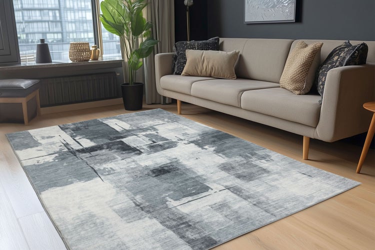 Wohnzimmer mit modernem Teppich mit abstraktem Muster vor einem Sofa auf einem hellen Holzboden.