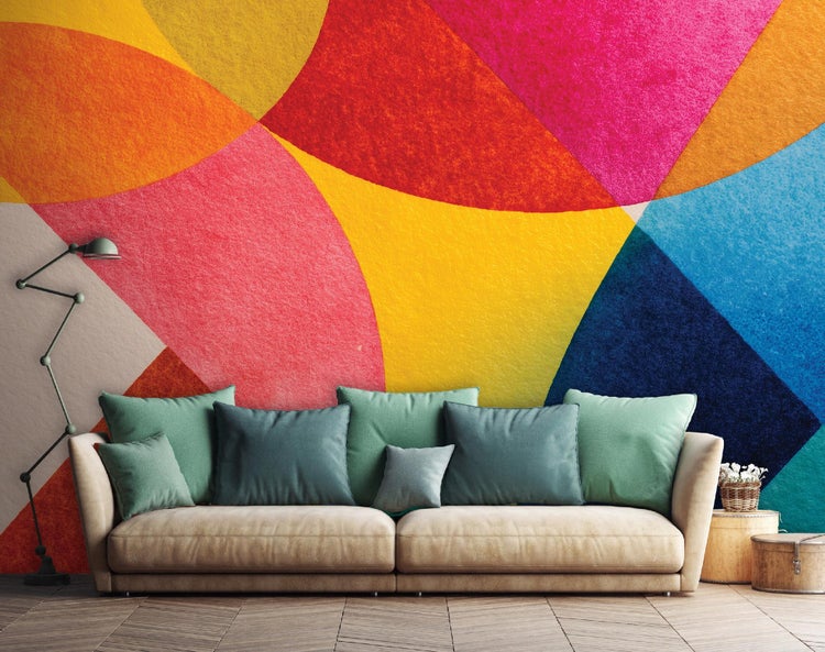 Wohnzimmer mit Sofa, Kissen und farbenfroher Wandgestaltung