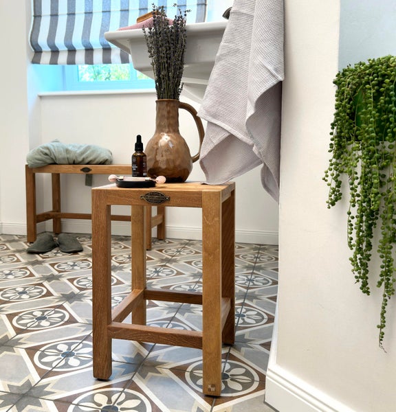 Badezimmer Interieur mit Holzbank, Hocker, Handtuch und Dekorationen auf gemusterten Fliesen