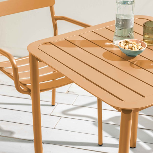 Moderner Metall-Gartentisch mit Lattenoberfläche und passendem Gartenstuhl auf einer hellen Holzterrasse.