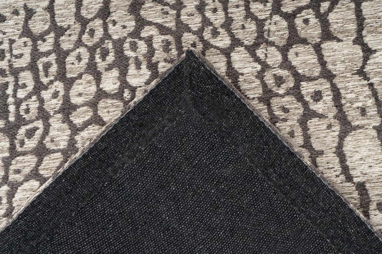 Nahaufnahme eines Teppichs mit Tiermuster und umgeknickter Ecke zur Ansicht der Rückseite.