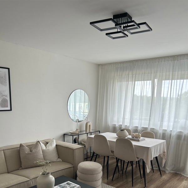 Wohnzimmer mit Sofa, Esstisch und quadratischer Deckenleuchte