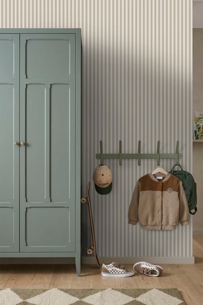 Gestreifte Tapete in einem organisierten Kinderzimmer mit grünem Kleiderschrank und Wandgarderobe.