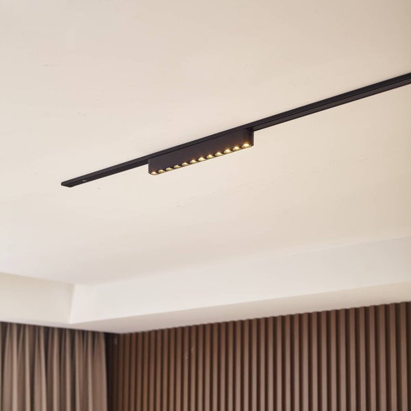 LED-Schienensystem mit linearem Leuchtkopf an der Decke eines hellen, modern gestalteten Raumes mit Holzelementen.