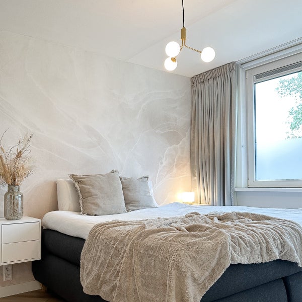 Schlafzimmer mit Bett, Nachttisch, Lampe und Vorhängen