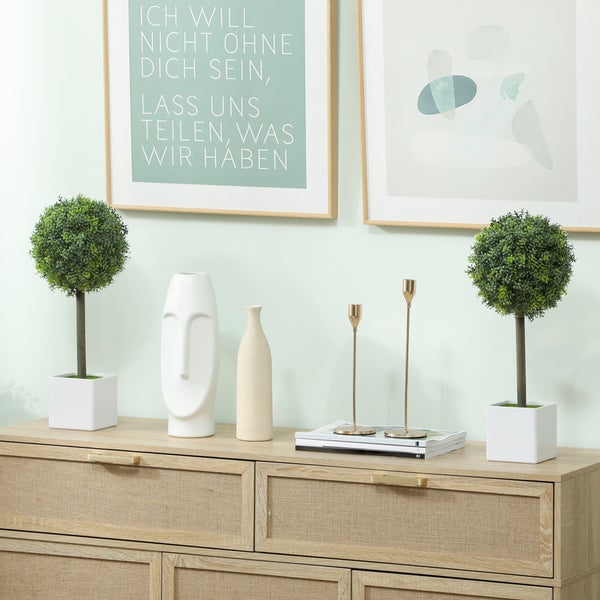 Dekoratives Sideboard mit zwei Topfpflanzen, einer Gesichtsvase, einer schmalen Vase und zwei Kerzenständern