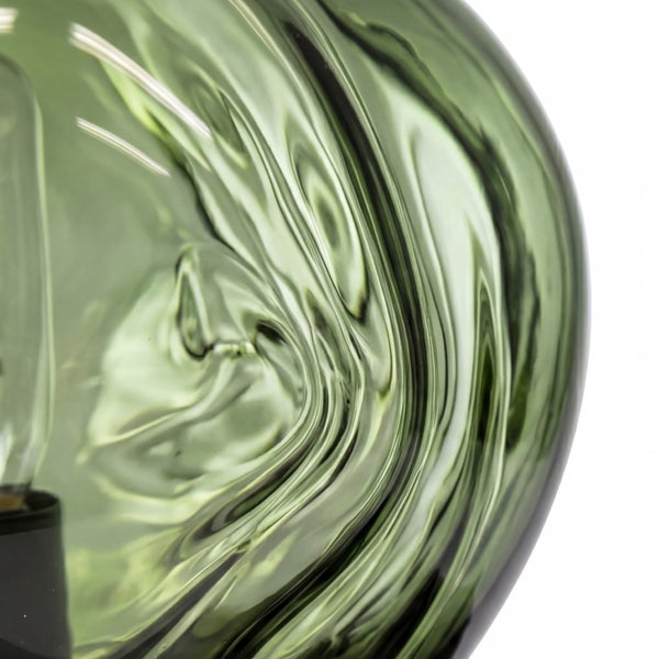 Detailaufnahme eines grünen Glaslampenschirms mit welliger Oberflächenstruktur und sichtbarem Leuchtmittel.