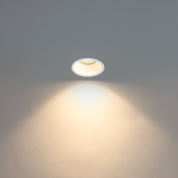 Eingeschalteter LED-Einbaustrahler, rund, weiß, mit warmweißem Lichtkegel.