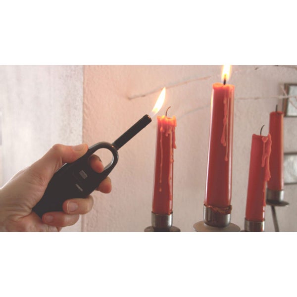 Eine Hand zündet mit einem Stabfeuerzeug Kerzen auf einem Kerzenständer an.