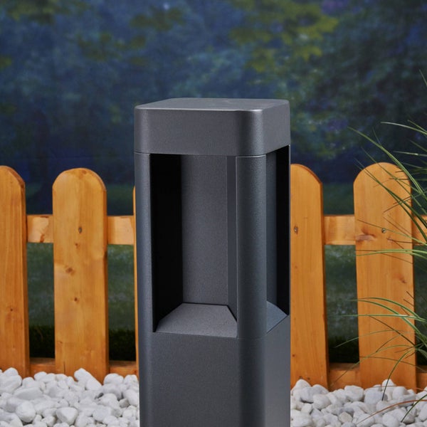 Moderne quadratische Wegeleuchte in Anthrazit vor einem Holzzaun im Garten auf weißen Steinen.
