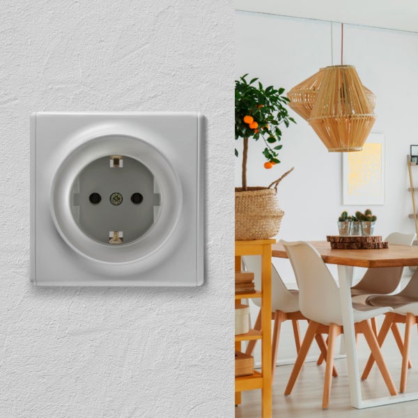 Eine moderne Steckdose an einer Wand neben einem hellen, wohnlichen Esszimmer mit Holztisch und Pendelleuchten.