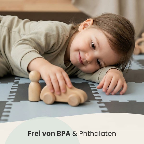 Ein Kind liegt auf einer Puzzlematte und spielt mit Holzspielzeug. Das Produkt ist frei von Bisphenol A und Phthalaten.