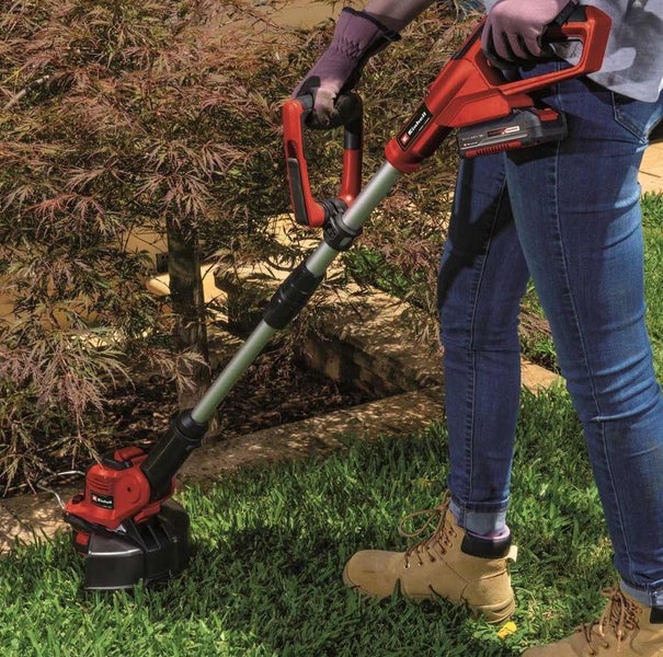 Person verwendet einen akkubetriebenen Einhell Rasentrimmer zur Gartenarbeit im Freien.