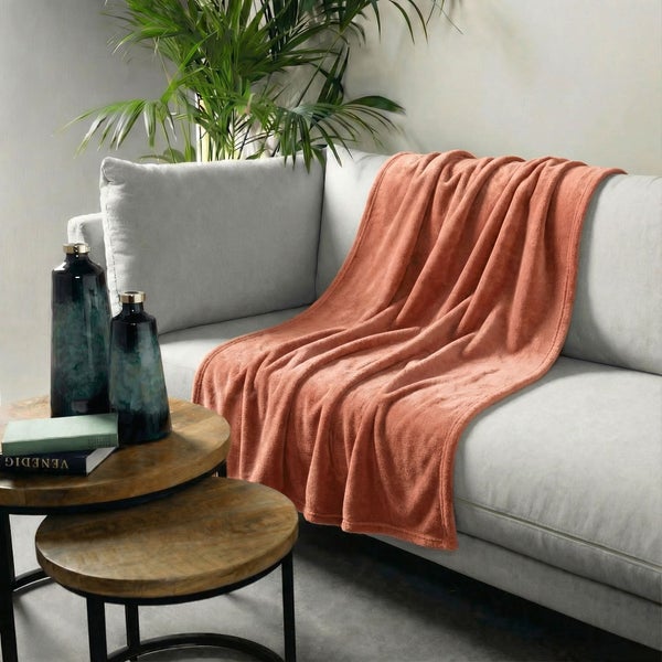 Wohnzimmer-Szene mit Sofa, Decke, Beistelltisch, Vasen und Pflanze für eine gemütliche Atmosphäre