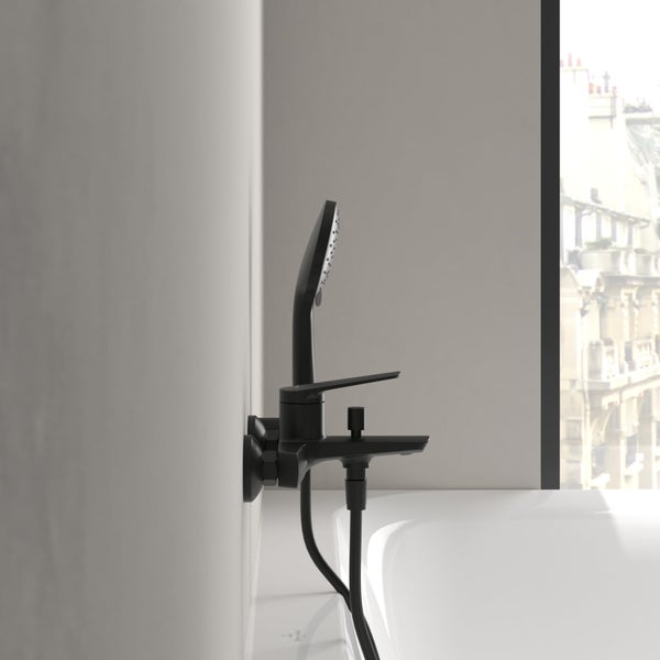 Schwarze Badewannenarmatur mit Handbrause vor einem Fenster