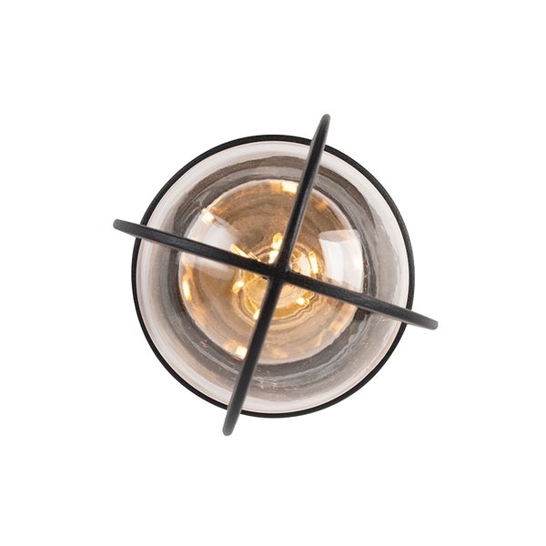 Runde Außenleuchte mit schwarzem Metallgitter und Glasabdeckung, warm leuchtend.