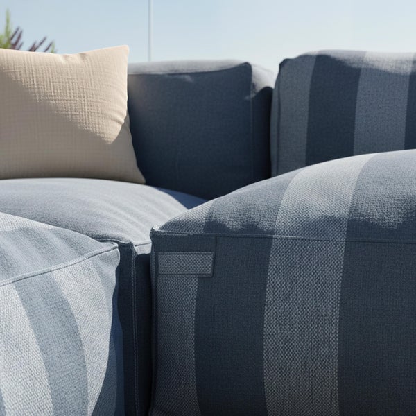 Nahaufnahme von Garten-Loungemöbeln mit gestreiftem Textilbezug und beigem Dekokissen.