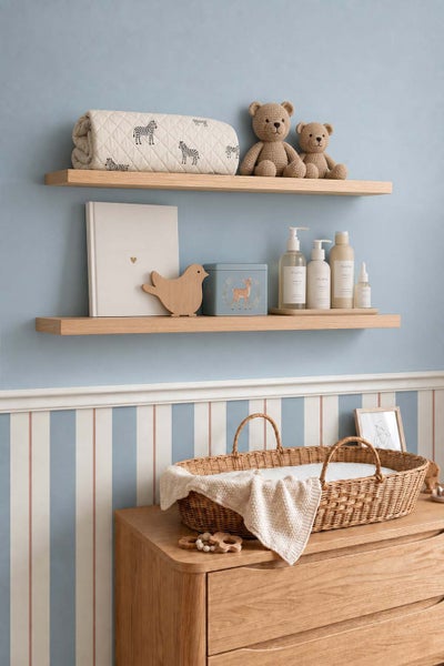 Wandregal aus Holz mit Kinderzimmerdekoration, Kuscheltieren und einem Weidenkorb auf einer Wickelkommode vor einer gestreiften Wand.