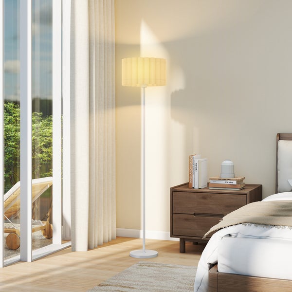 Stehleuchte in einem hellen Schlafzimmer neben einem Nachttisch.