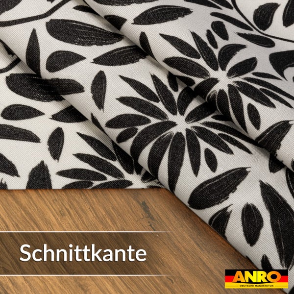 Stoffmeterware mit floralem Blattmuster und Blüten auf Holzoberfläche mit Fokus auf die Schnittkante. ANRO Logo.