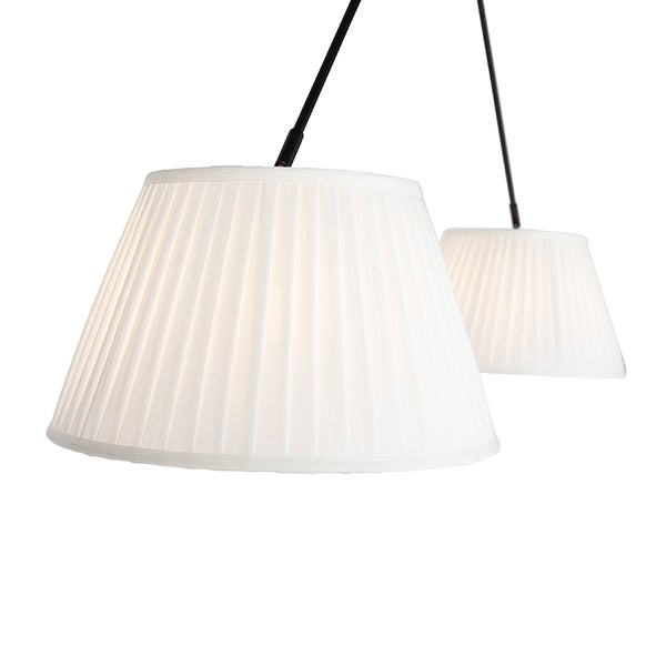 Zwei plissierte Stoffschirme einer Pendelleuchte an schwarzen Metallstangen.