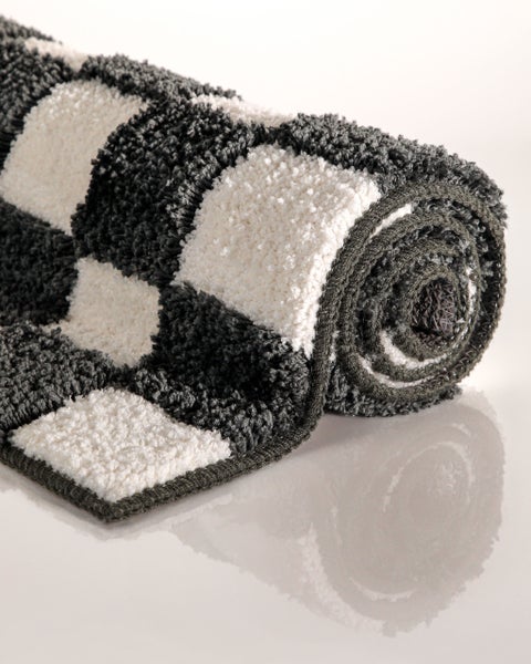 Hochflor-Badteppich mit Karomuster, weiches Material, aufgerollt.