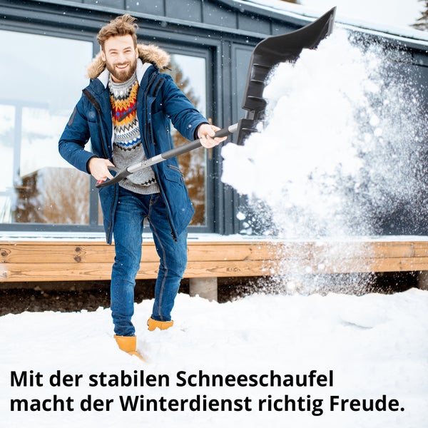 Mann schaufelt Schnee mit einer Schneeschaufel vor dem Haus