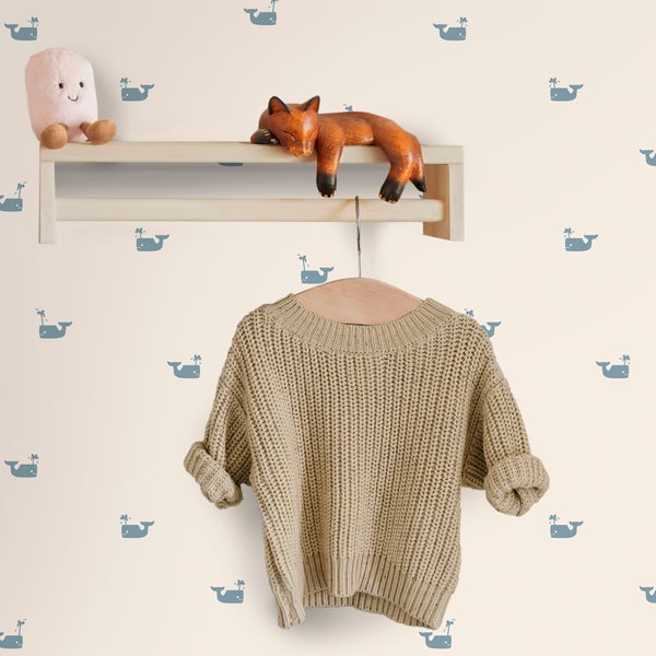 Kindertapete mit Wal-Motiv in einem Kinderzimmer mit Holzregal und Kleiderstange.