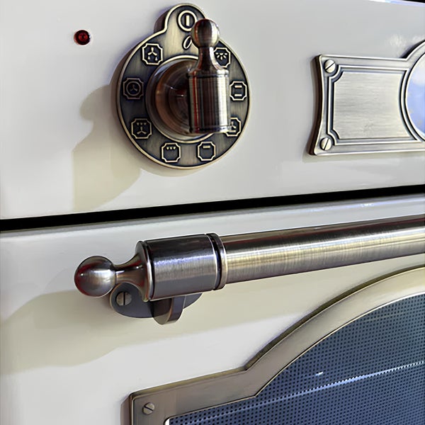 Detailansicht eines Einbauofens im Landhausstil mit Bedienknebeln, metallischem Türgriff und dekorativen Beschlägen.
