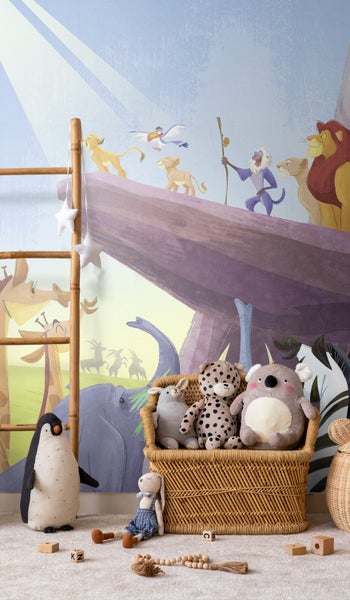 Kinderzimmer mit einer Wandtapete von der König der Löwen, einem geflochtenen Korb und verschiedenen Stofftieren.