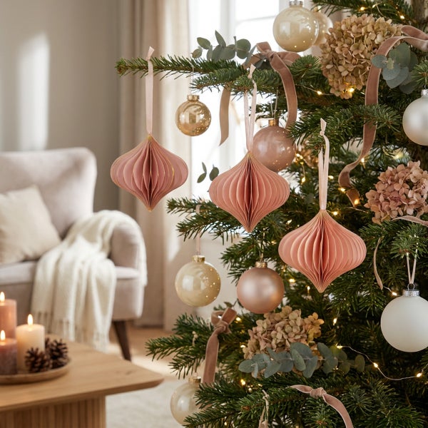 Weihnachtsbaum geschmückt mit Papieranhängern in Zwiebelform, glänzenden Kugeln, Trockenblumen und Lichterkette in einem wohnlichen Raum.