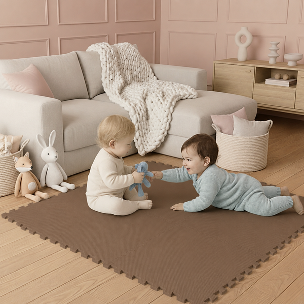 Zwei Kleinkinder spielen auf dunkelbraunen Schaumstoff-Puzzlematten in einem modern eingerichteten Wohnzimmer mit Sofa und Holzboden.