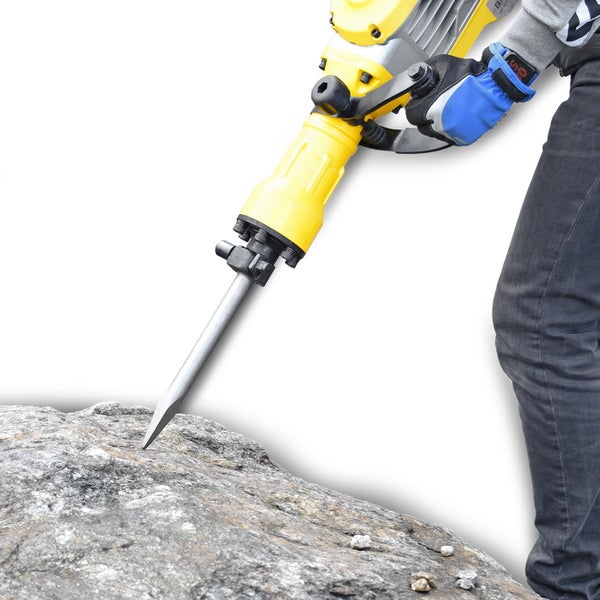Person bedient einen gelben Abbruchhammer auf einem Stein.