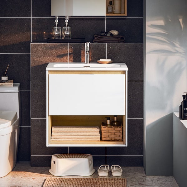 Modernes Badezimmer mit Waschbeckenunterschrank, Armatur und Ablageflächen für Badutensilien.