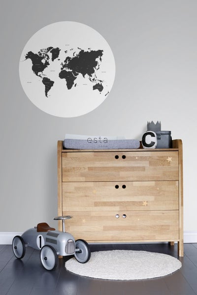 Szene mit einer Holzkommode, einem Globus, einem Spielzeugauto und einem runden Teppich in einem Kinderzimmer