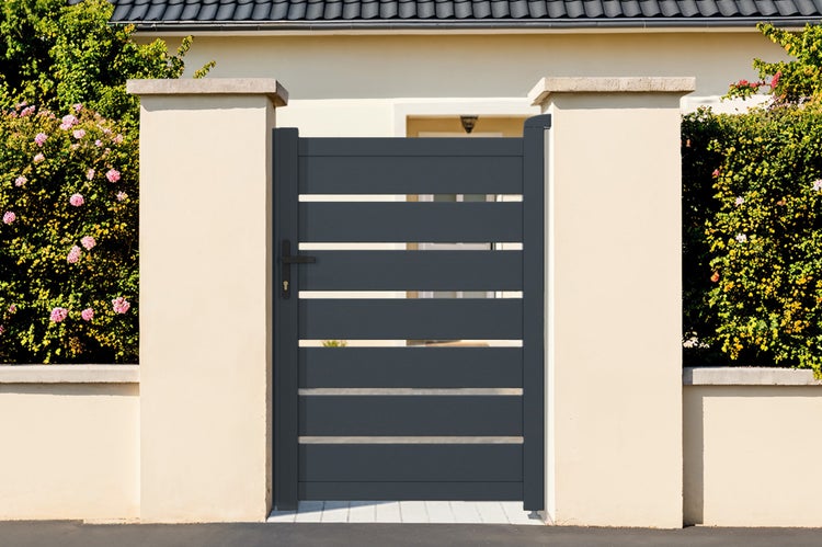 Modernes Gartentor aus Aluminium in Anthrazit mit horizontalen Lamellen, montiert zwischen hellen Mauerpfeilern vor einem Hauseingang.