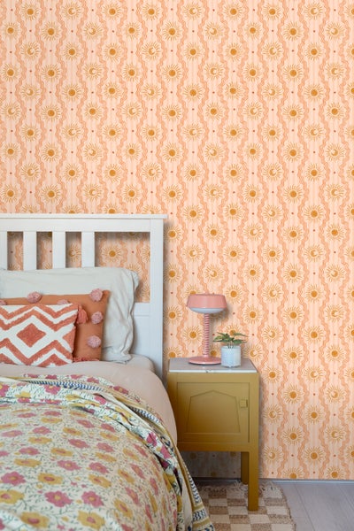 Schlafzimmer mit Bett und Nachttisch vor einer Wand mit Sonne Mond Tapete.