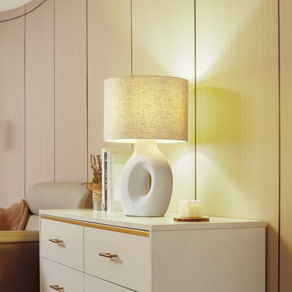 Dekorative Tischlampe mit Stoffschirm und Keramikfuß auf einem Nachttisch