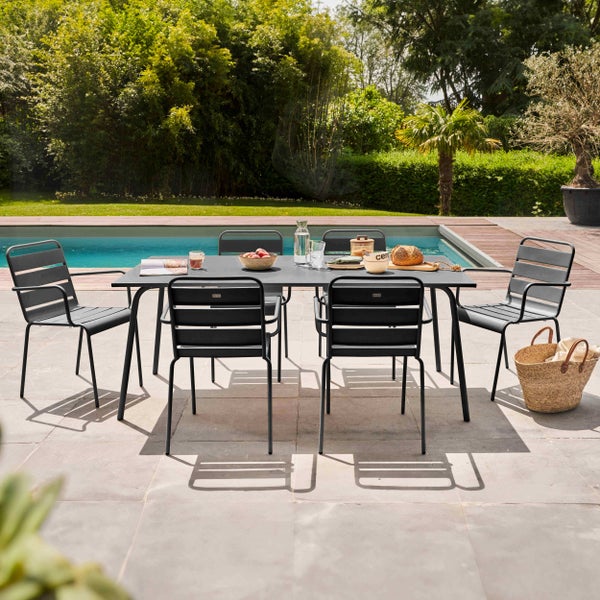 Gartenmöbel-Set mit rechteckigem Metalltisch und sechs Stühlen auf einer gepflasterten Terrasse am Swimmingpool.