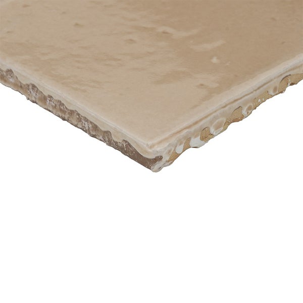 Beige Wandfliese mit unebener Oberfläche und unregelmäßiger Kante in Nahaufnahme