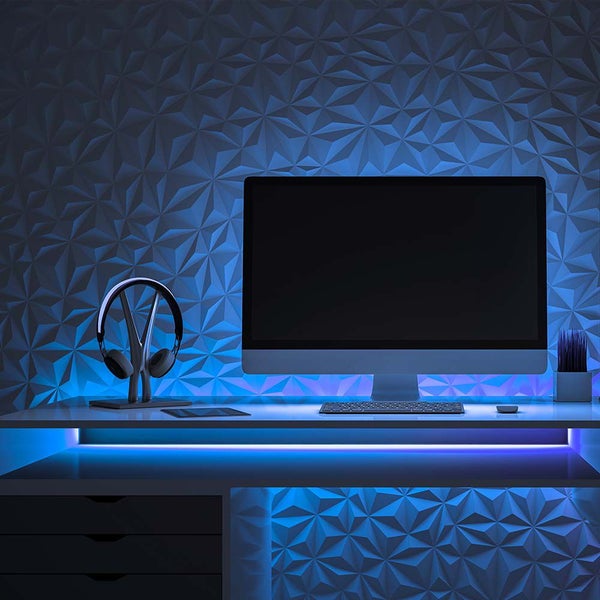 Szene eines Schreibtisches mit Computermonitor, Tastatur, Kopfhörern und strukturierten Wandpaneelen
