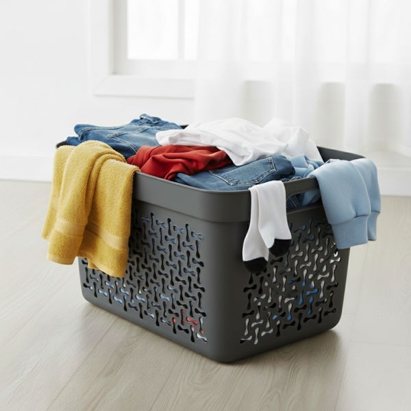 Wäschekorb aus Kunststoff mit Kleidung im Raum