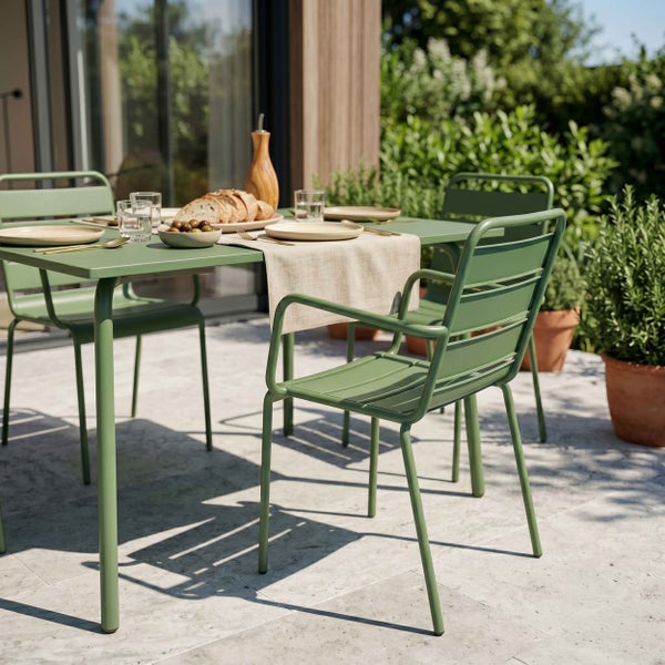 Modernes Gartenmöbel-Set aus grünem Metall mit Tisch und Stühlen auf einer hellen Steinterrasse, gedeckt für eine Mahlzeit im Freien.