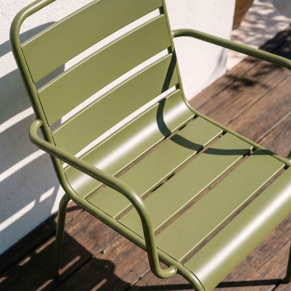Moderner olivgrüner Gartenstuhl mit Armlehnen und Lamellen aus Metall auf einer hellen Holzterrasse.