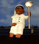 Solarleuchte als Gartenfigur Sandmännchen sitzend auf einer Dachrinne mit leuchtender Lampe.