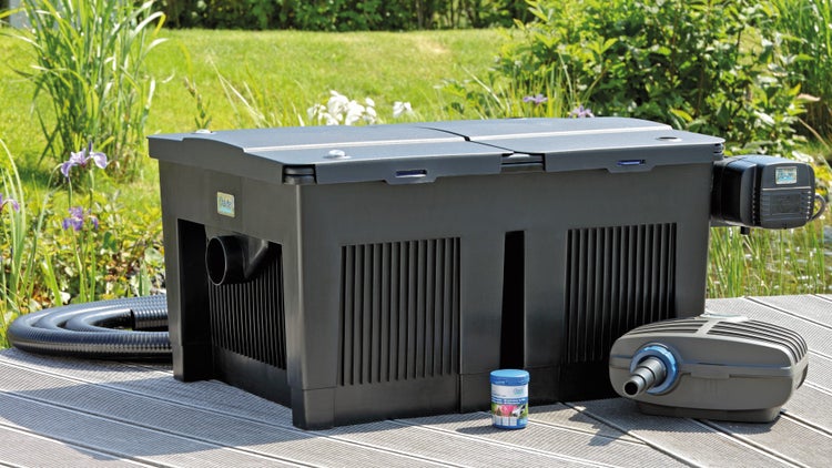 Oase Teichfilter-Set FiltoMatic CWS mit Pumpe, Schlauch und Starterbakterien auf einer Holzterrasse im Garten.