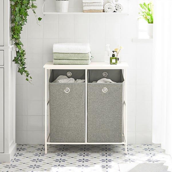 Badezimmer mit Wäschetruhe, Handtüchern und Dekoration auf gefliestem Boden