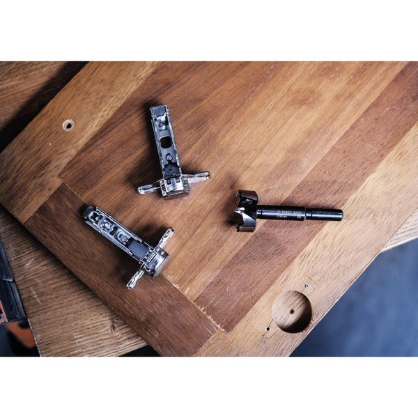 Eine Person bohrt mit einer Akku-Bohrmaschine ein Loch in ein Holzbrett.