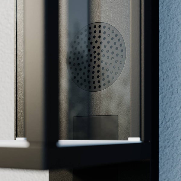 Detailansicht eines modernen Türkommunikationssystems mit Lautsprechergitter hinter Glas, an einer Wand montiert.