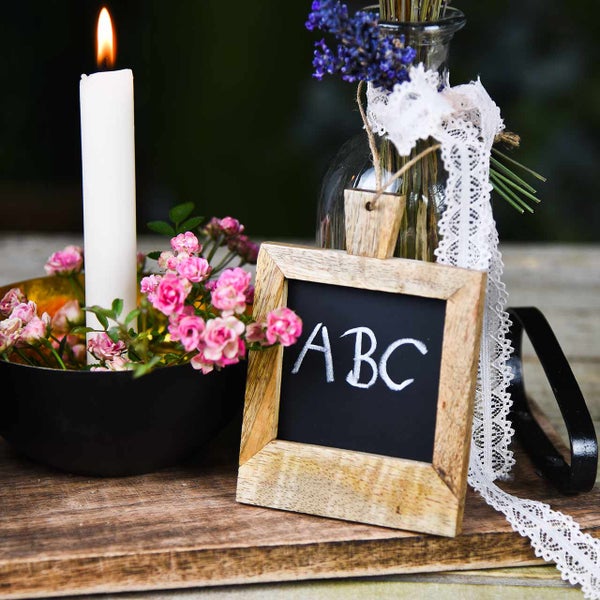 Dekoration mit Kerze, Rosen, Tafel und Lavendel in einer Vase